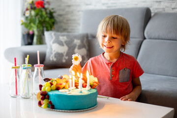 Cute preschool boy with birthday cake with candles at home, preparing for party