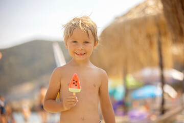 Happy child, boy eating ice cream  on the beach, enjoying summer, playing