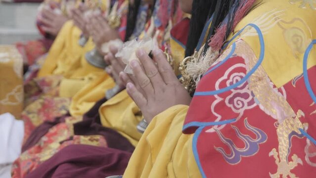 Row of Tantric tibetan buddhist monks in namaste mudra, at fire puja with dorje and bell in their hands, chanting mantras in overtone singing or, throat singing.
