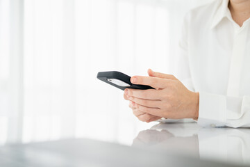 Cropped shot of woman typing on cellphone over blurred background. Close up of female hands texting on smartphone