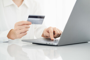Woman hand holding credit card and using laptop at home, online shopping and paying bills, Payment method.