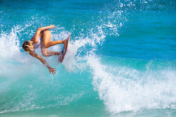 Skimboarder riding an ocean wave; Sandy Beach, Oahu, Hawaii, United States of America