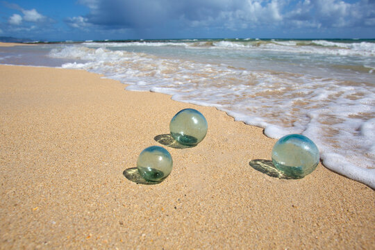 Japanese fishing balls, glass floats, on the wet sand of a beach with sea surf, Maui, Hawaii, USA