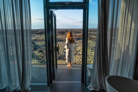Fototapeta Woman standing on balcony in a bathrobe overlooking the lava fields in Southern Iceland  Blue Lagoon, South Iceland, Iceland