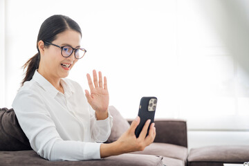 Happy mature asian woman waving hand using smartphone app enjoying online virtual chat video call with friends in distance mobile chat virtual meeting, recording stories for social media at home.