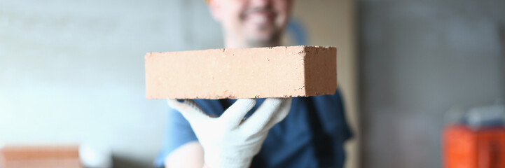 Master builder man holding red brick at construction site. Brick laying master concept