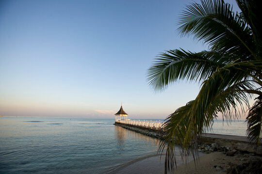 Sea surrounds a pavilion and pier at sunset at a resort in Jamaica; Jamaica
