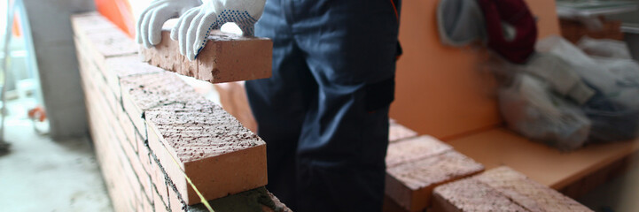 Closeup of industrial bricklayer laying bricks at construction site. Repair building and brickwork