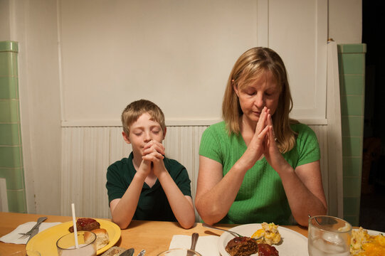 Mother and son sit at the kitchen table and pray before dinner; Lincoln, Nebraska, United States of America