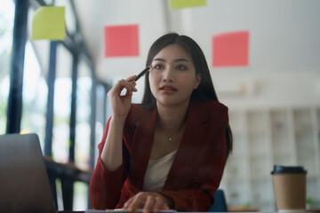 Beautiful young teen asian businesswoman using note pad thinking  with planning working on financial document, tax, exchange, accounting and Financial advisor