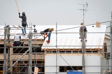 新築工事現場の屋根で働く男性作業員