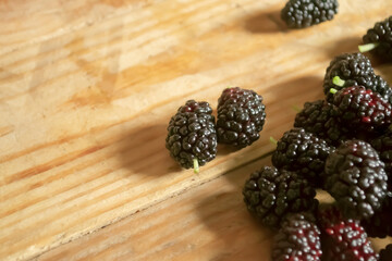 Mulberries on a wooden table. Lots of black mulberries on a wooden table. Useful summer berries.