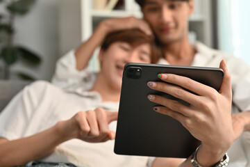 Selective focus on hand holding tablet, Asian teenage gay couple using digital tablet together.
