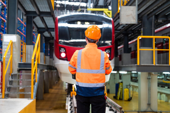 Caucasian Man Wearing Safety Uniform And Helmet Standing Hand Signaling For Trains To Enter The Tracks To Inspect Trains For Maintenance At The Train Depot.