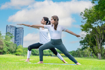 Fototapeta na wymiar Asian womanYoga teacher and Caucasian girls in sports pants, balance training, yoga poses in park health and fitness concept
