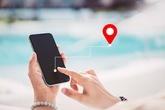 Woman hand using smart phone with navigator location point at tropical sunset beach abstract background. Technology interenet and travel adventure concept. Vintage tone filter color style.