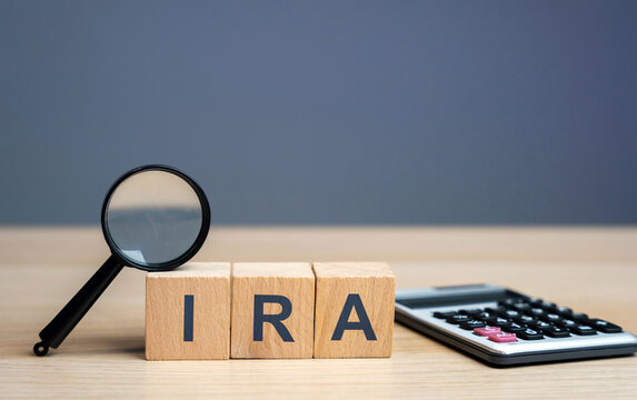 Wooden blocks with the word IRA - individual retirement account. Tax-advantaged account that individuals use to save and invest for retirement. Business and finance concept