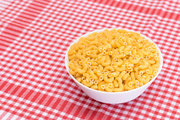 Uncooked Chifferi Rigati Pasta in White Cup on Red Checkered Towel. Fat and Unhealthy Food. Classic Dry Macaroni. Italian Culture and Cuisine. Raw Pasta