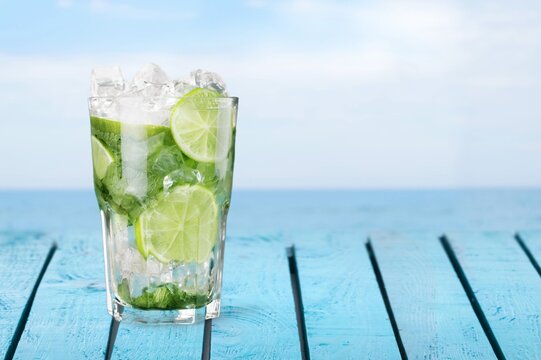 Tasty sweet alcohol cocktail in glass on beach background