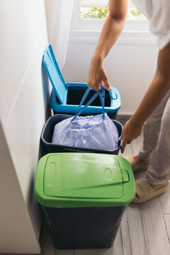 High angle of anonymous crop woman taking out garbage bag from a container