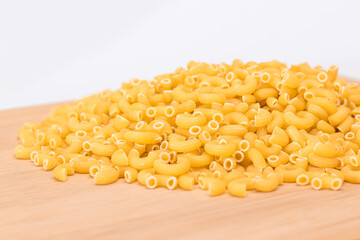 A Heap of Uncooked Chifferi Rigati Pasta on Wooden Kitchen Board. Fat and Unhealthy Food. Classic Dry Macaroni. Italian Culture and Cuisine. Raw Pasta