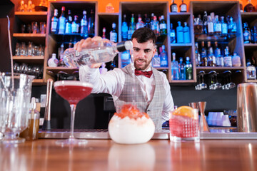 Young cocktail bartender making a special cocktail for his clients. Concept: drinks, fun, nightlife