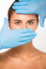 Hands wearing surgical gloves covering woman's face.