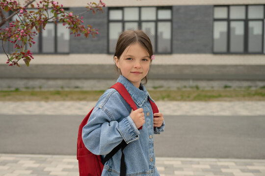 Serious little girl with backpack on street