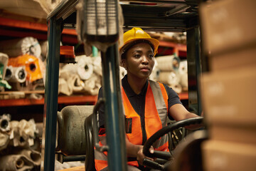 Young African female forklift operator at work in a textile storehouse