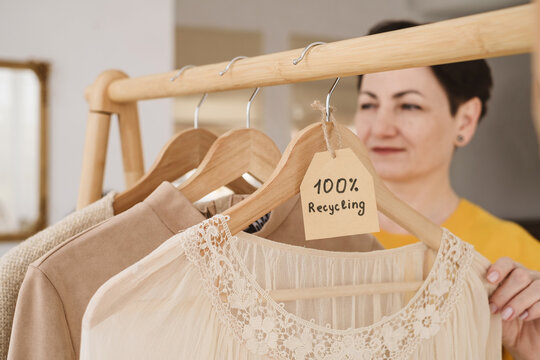 Blurred female near clothes hanging on wooden hangers