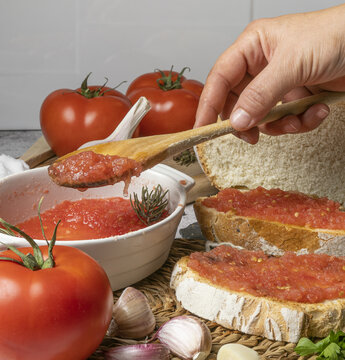 Crop hand of anonymous chef taking tomato spread from bowl with spoon