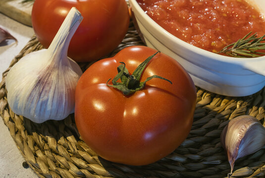 Ripe tomatoes and garlic near bowl with tomato spread