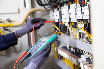 Electrician engineer tests electrical installations and wires on relay protection system....