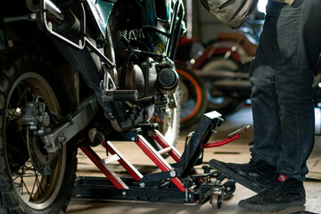 Creative authentic motorcycle workshop Garage biker mechanic repairs motorcycle jacks it up