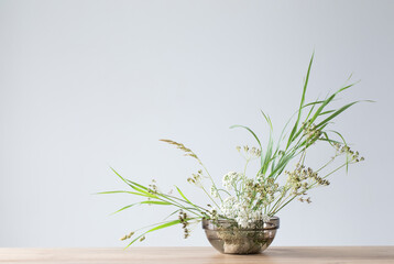 arrangement of wild flowers and plants in  glass bowl on  gray background