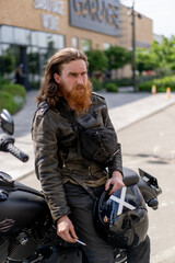 Fototapeta na wymiar brutal red bearded biker sitting on a black motorcycle after a race smoking a cigarette thirst for speed motorsport concept