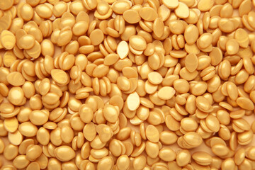 Background texture of beige depilatory wax and wooden spatulas. Depilation wax granules. Epilation, depilation, unwanted hair removal.