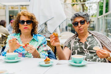 Positive middle age women with desserts in outdoor cafe