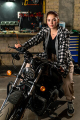 Creative authentic motorcycle workshop garage beautiful young girl biker sitting on a cool motorcycle