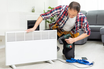 Quality help. Handyman using pipe wrench while repairing radiator battery in the room. Heating restoration