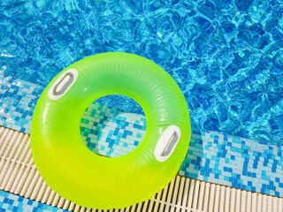 Bright inflatable tube ring floating on blue water surface, in swimming pool during sunny...