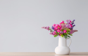 beautiful flowers in white jug on wooden shelf