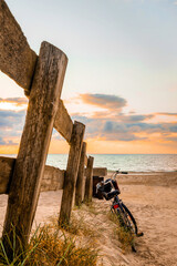 Fahrrad und Holzzaun am Strand zur blauen Stunde vor dem Sonnenuntergang, vertikal 