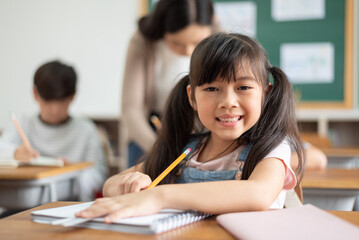 Portrait of Asian Chinese school girl with pigtails in classroom