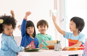 Diversity MultiEthnic Children raising hands up in classroom at school