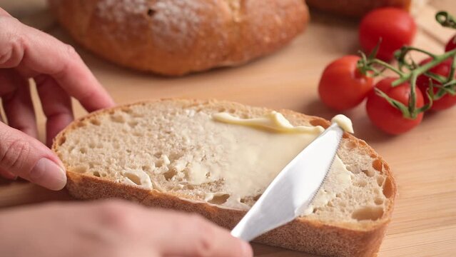 Woman spreading soft butter on slice of bread. Spreading cream cheese on bread. Housewife making sandwich for breakfast.
