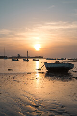 Fototapeta na wymiar Small fishing boats at low tide during a sunset in Cadiz.