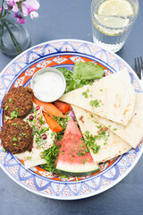 Summer arabic salad with falafel, hummus, water melon, carrots, lettuce, carrots, dressing and pita bread  - 615534206