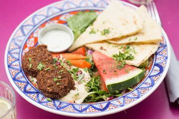 Summer arabic salad with falafel, hummus, water melon, carrots, lettuce, carrots, dressing and pita bread  - 615534412