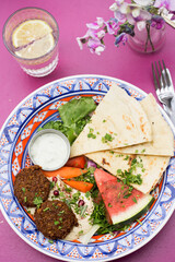 Summer arabic salad with falafel, hummus, water melon, carrots, lettuce, carrots, dressing and pita bread  - 615535271
